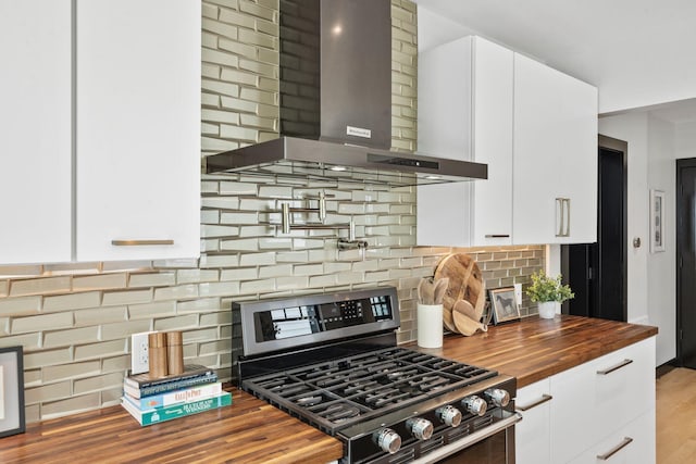 252 Cochran Rd, Lexington, KY 40502 - kitchen featuring stainless steel range with gas stovetop, wall chimney range hood, butcher block countertops, white cabinetry, and decorative backsplash