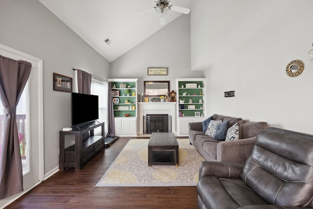 living area featuring high vaulted ceiling, healthy amount of natural light, a fireplace, and dark wood-type flooring