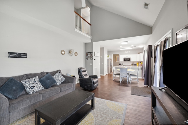 living room with wood finished floors, high vaulted ceiling, and baseboards
