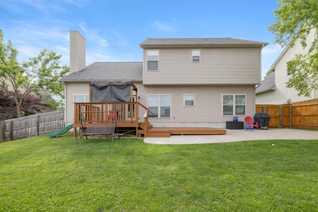 rear view of house with a deck, a chimney, a patio area, a playground, and roof with shingles