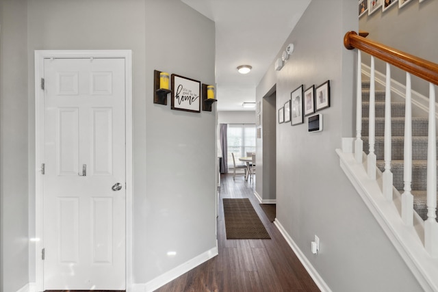 hallway with baseboards, dark wood-type flooring, and stairs