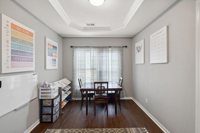 dining space with dark wood-style floors, crown molding, baseboards, and a tray ceiling