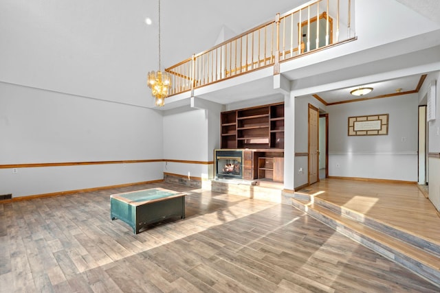 10708 Battlefield Memorial Hwy, Berea, KY 40403 - unfurnished living room with baseboards, a towering ceiling, a glass covered fireplace, wood finished floors, and a chandelier