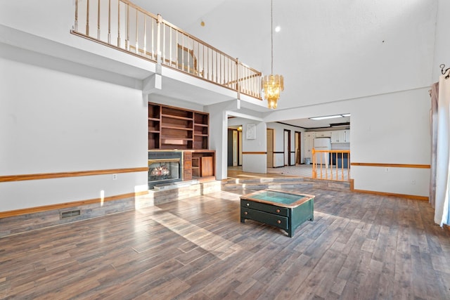 10708 Battlefield Memorial Hwy, Berea, KY 40403 - unfurnished living room with a towering ceiling, a fireplace, wood finished floors, baseboards, and a chandelier