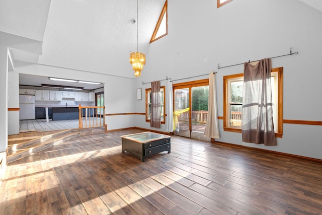 10708 Battlefield Memorial Hwy, Berea, KY 40403 - unfurnished living room with wood finished floors, high vaulted ceiling, baseboards, and a chandelier