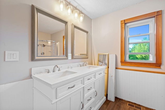 10708 Battlefield Memorial Hwy, Berea, KY 40403 - bathroom featuring wood finished floors, double vanity, a wainscoted wall, a textured ceiling, and a shower