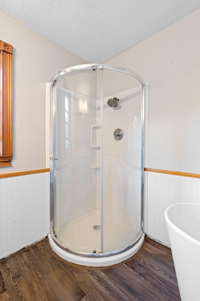 10708 Battlefield Memorial Hwy, Berea, KY 40403 - bathroom with wainscoting, wood finished floors, a stall shower, a soaking tub, and a textured ceiling
