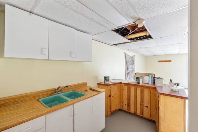 10708 Battlefield Memorial Hwy, Berea, KY 40403 - kitchen featuring a paneled ceiling, a sink, white cabinetry, light countertops, and concrete flooring