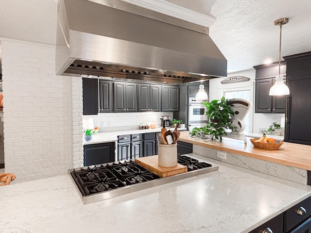 1610 Steele Branch Rd, West Liberty, KY 41472 - kitchen featuring wall chimney exhaust hood, stainless steel gas stovetop, a textured ceiling, decorative light fixtures, and backsplash