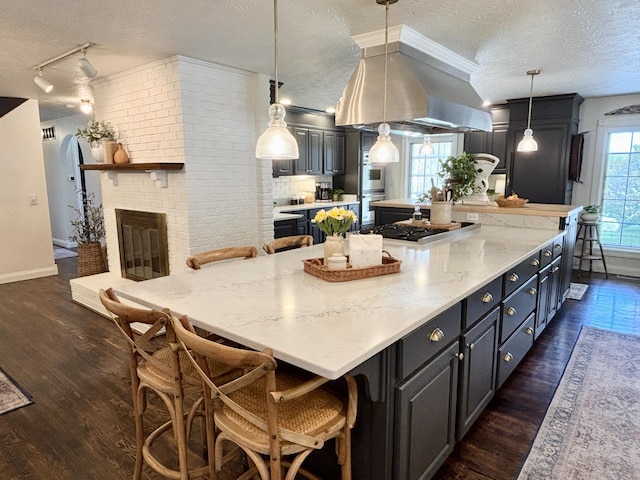 1610 Steele Branch Rd, West Liberty, KY 41472 - kitchen featuring a textured ceiling, gas cooktop, dark wood-type flooring, a breakfast bar area, and a large island