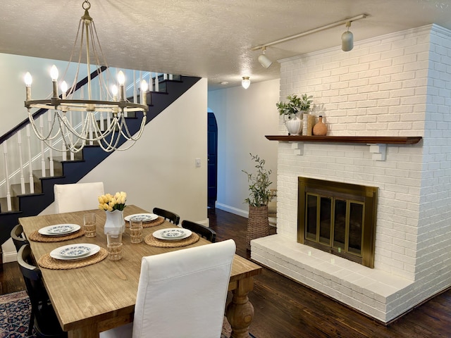 1610 Steele Branch Rd, West Liberty, KY 41472 - dining space featuring stairs, baseboards, wood finished floors, rail lighting, and a brick fireplace