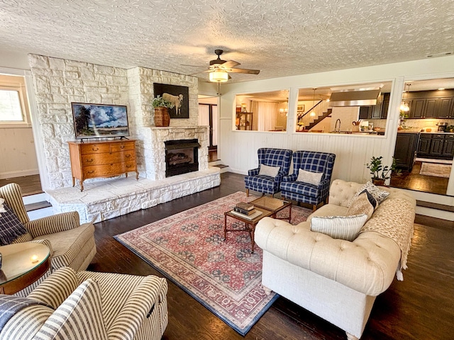 1610 Steele Branch Rd, West Liberty, KY 41472 - living area with wood finished floors, a ceiling fan, a stone fireplace, and a textured ceiling