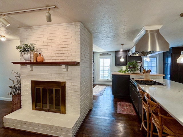 1610 Steele Branch Rd, West Liberty, KY 41472 - kitchen featuring a textured ceiling, island exhaust hood, stainless steel gas stovetop, dark wood-style flooring, and a fireplace