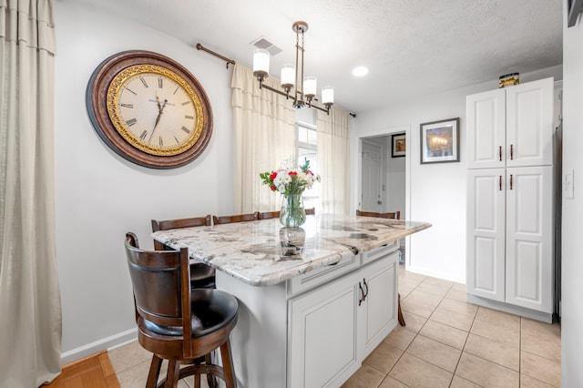 356 Weslyn Way, Nicholasville, KY 40356 - kitchen featuring light stone countertops, a kitchen breakfast bar, light tile patterned floors, decorative light fixtures, and white cabinetry
