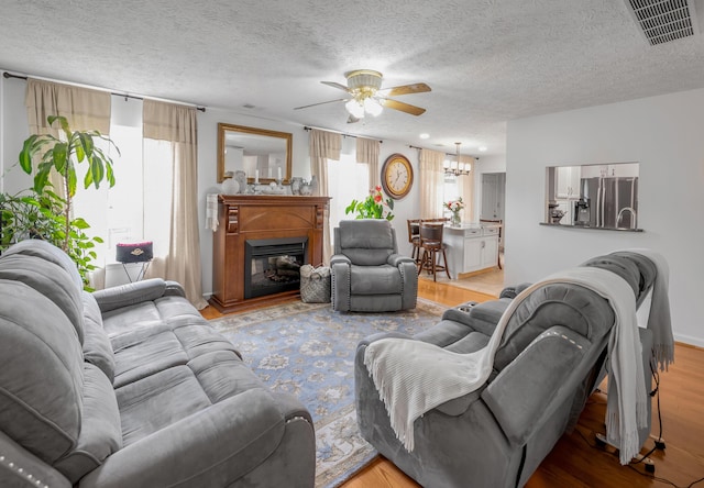 356 Weslyn Way, Nicholasville, KY 40356 - living area with ceiling fan, wood finished floors, a chandelier, a glass covered fireplace, and a textured ceiling
