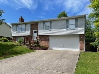 402 Mcdowell Dr, Winchester, KY 40391 - bi-level home featuring an attached garage, concrete driveway, a chimney, and brick siding