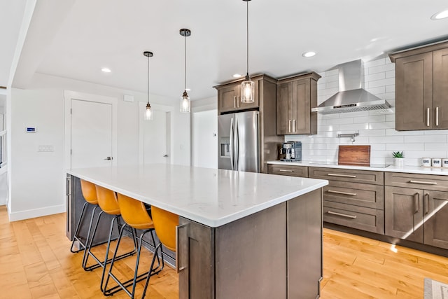 1251 Wilmore Rd, Nicholasville, KY 40356 - kitchen featuring stainless steel refrigerator with ice dispenser, wall chimney range hood, tasteful backsplash, a kitchen island, and light wood-type flooring