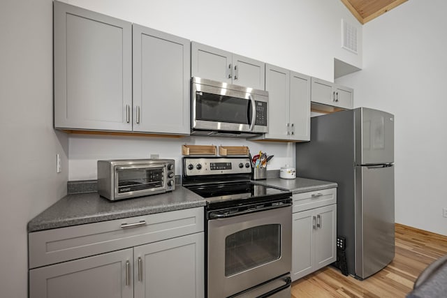 3786 Shoemaker Rdg, Beattyville, KY 41311 - kitchen with appliances with stainless steel finishes, gray cabinetry, dark countertops, and light wood-type flooring