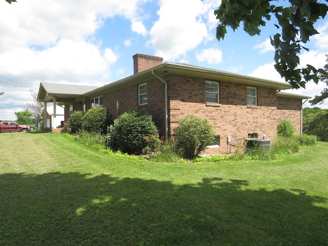 498 Winding Blade Rd, East Bernstadt, KY 40729 - view of home's exterior featuring a chimney, a yard, brick siding, and central AC