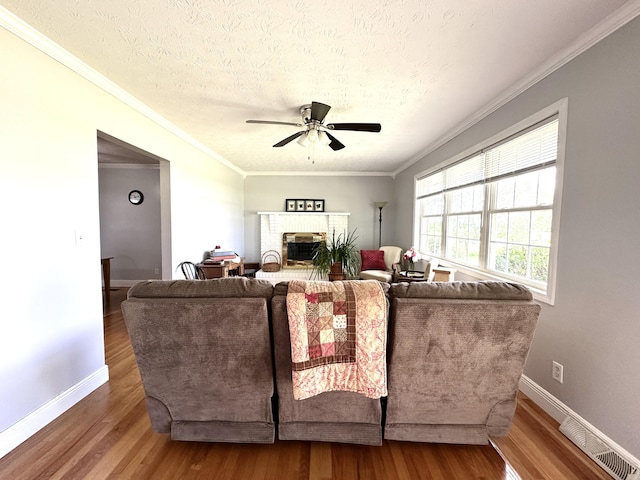 498 Winding Blade Rd, East Bernstadt, KY 40729 - living room with crown molding, wood finished floors, a ceiling fan, baseboards, and a brick fireplace