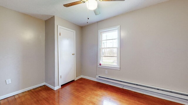 220 Johnson Ln, Berea, KY 40403 - unfurnished bedroom featuring a baseboard radiator, wood finished floors, baseboards, and ceiling fan