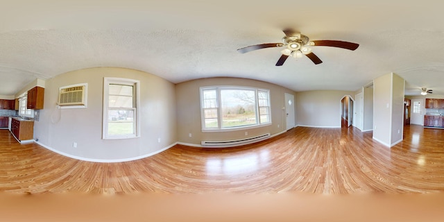 220 Johnson Ln, Berea, KY 40403 - unfurnished living room featuring baseboard heating, light wood-style floors, baseboards, a wall mounted air conditioner, and ceiling fan
