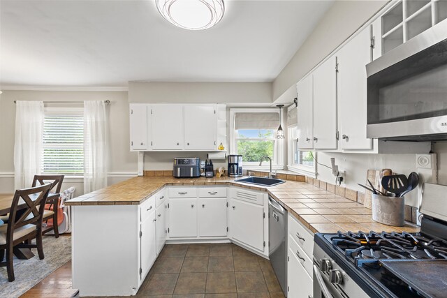 298 Hill N Dale Rd, Lexington, KY 40503 - kitchen with stainless steel appliances, a sink, a peninsula, white cabinets, and tile counters