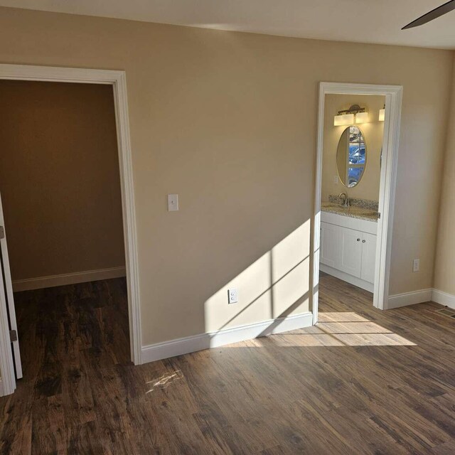135 Watkins Branch Rd, East Bernstadt, KY 40729 - unfurnished bedroom featuring wood finished floors, baseboards, a sink, and connected bathroom