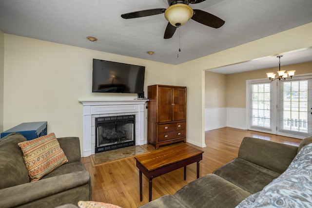 113 Medinah Ct, Frankfort, KY 40601 - living room with light wood-style flooring, a tiled fireplace, ceiling fan, and a chandelier