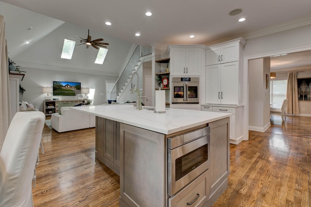 1304 Wakehurst Ct, Lexington, KY 40509 - kitchen featuring stainless steel appliances, white cabinets, a skylight, ceiling fan, and a center island with sink