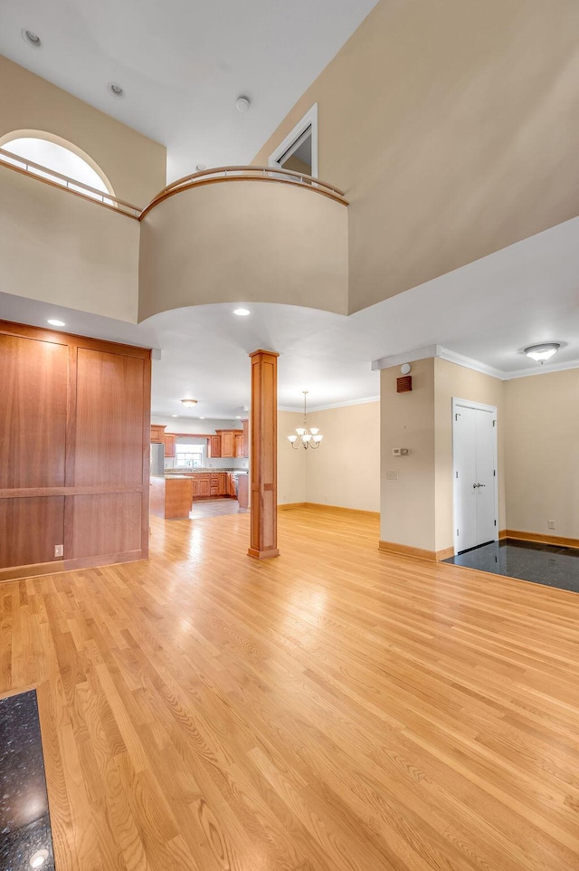 400 Redding Rd # 2, Lexington, KY 40517 - unfurnished living room with ornate columns, light wood-style flooring, a chandelier, a towering ceiling, and baseboards