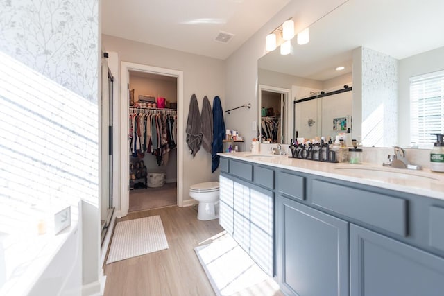 133 Kirkstall Way, Georgetown, KY 40324 - bathroom featuring a shower stall, a walk in closet, wood finished floors, double vanity, and wallpapered walls