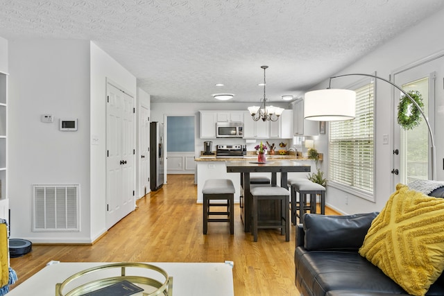 481 Alderbrook Way, Lexington, KY 40515 - dining room with a chandelier, light wood-style flooring, a textured ceiling, and baseboards