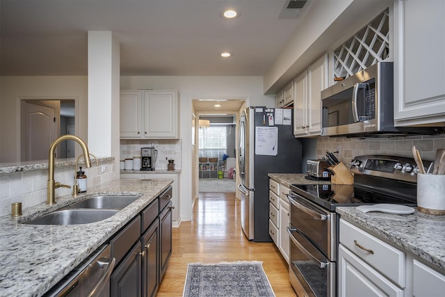 3657 Gladman Way, Lexington, KY 40503 - kitchen with appliances with stainless steel finishes, a sink, backsplash, white cabinets, and light wood-style floors