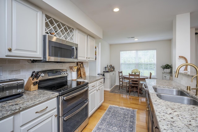 3657 Gladman Way, Lexington, KY 40503 - kitchen with stainless steel appliances, a sink, white cabinets, backsplash, and light wood-type flooring