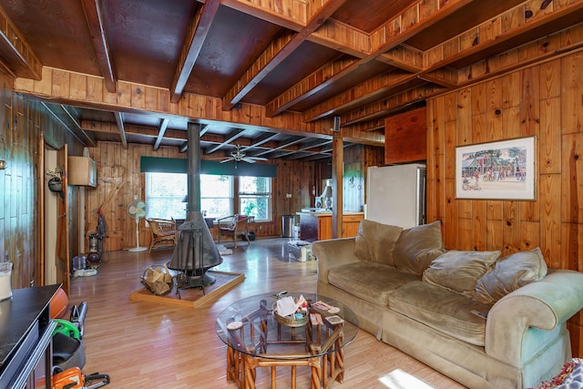 274 Oster Dr, Harrodsburg, KY 40330 - living area featuring wood walls, wood finished floors, beam ceiling, a wood stove, and a ceiling fan