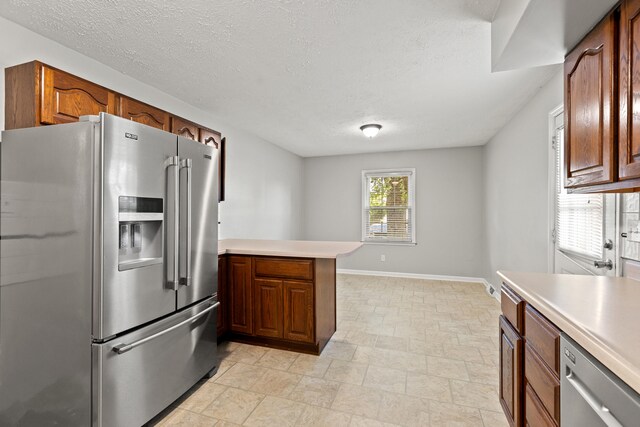 2371 Pierson Dr, Lexington, KY 40505 - kitchen featuring appliances with stainless steel finishes, a peninsula, light countertops, baseboards, and a textured ceiling