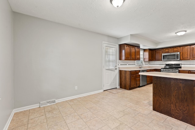 2371 Pierson Dr, Lexington, KY 40505 - kitchen featuring stainless steel appliances, light countertops, a textured ceiling, baseboards, and decorative backsplash