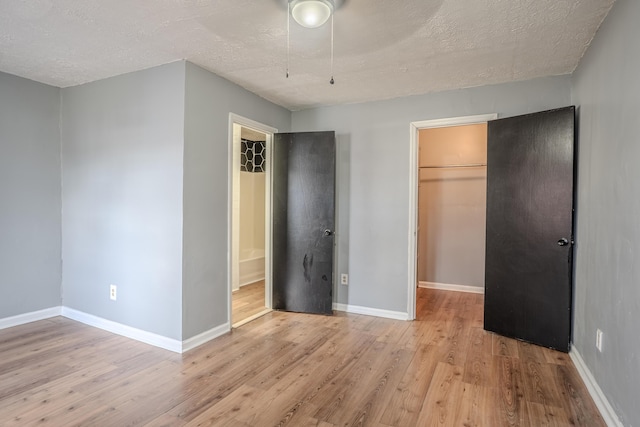 108 Rancho Ct, Frankfort, KY 40601 - unfurnished bedroom featuring a walk in closet, light wood-type flooring, a closet, baseboards, and a textured ceiling