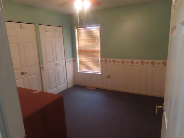3200 US-60 W, Morehead, KY 40351 - unfurnished bedroom with a wainscoted wall, multiple closets, and dark colored carpet