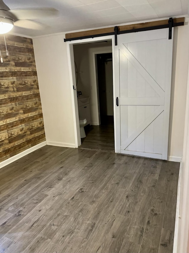 21544 Ky Route 122, Mcdowell, KY 41647 - empty room with a barn door, a ceiling fan, wood walls, wood finished floors, and baseboards