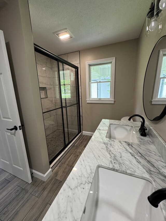 83 Gene Conner Rd, Russell Springs, KY 42642 - full bathroom with wood finished floors, a textured ceiling, a stall shower, baseboards, and double vanity