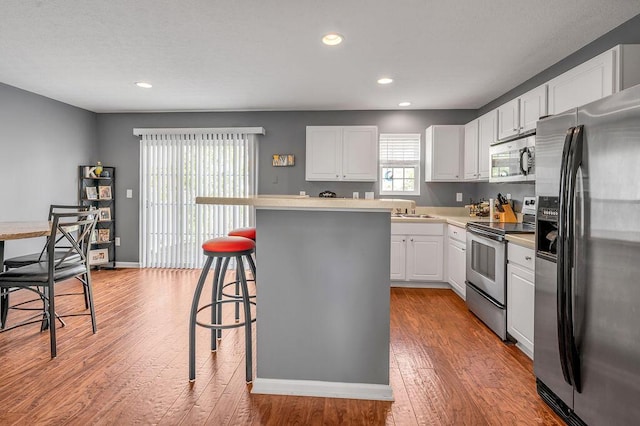 2433 Aristocracy Cir, Lexington, KY 40509 - kitchen with appliances with stainless steel finishes, a kitchen breakfast bar, white cabinetry, wood-type flooring, and recessed lighting