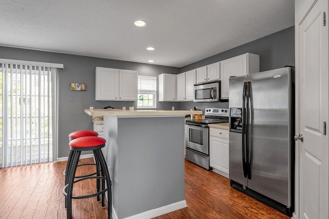 2433 Aristocracy Cir, Lexington, KY 40509 - kitchen with stainless steel appliances, white cabinetry, a breakfast bar, light countertops, and wood finished floors