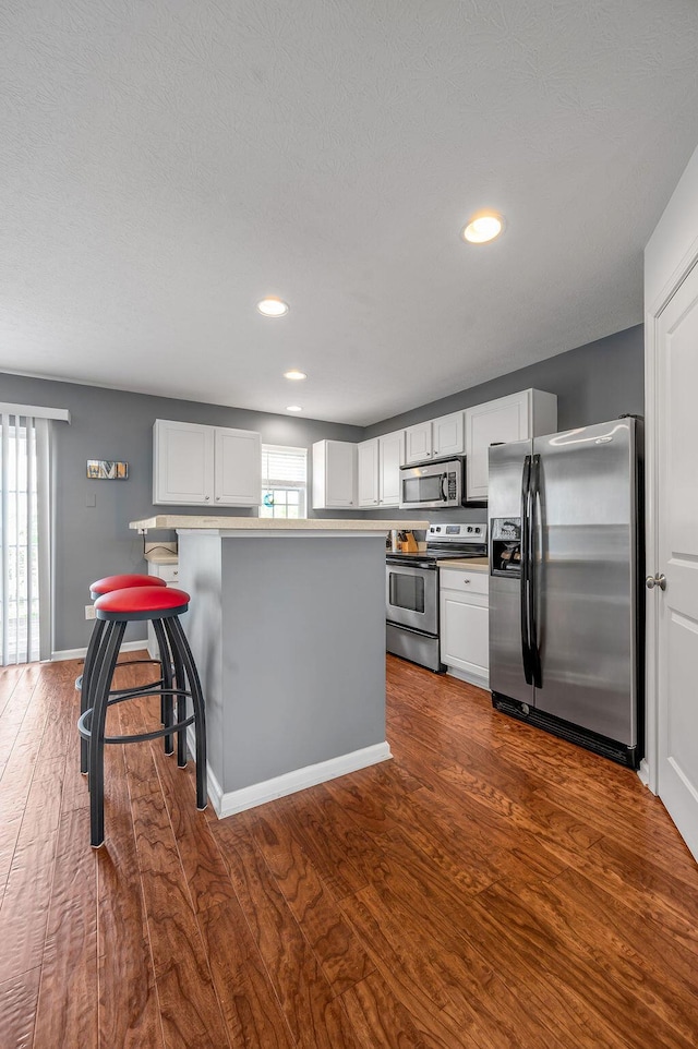 2433 Aristocracy Cir, Lexington, KY 40509 - kitchen featuring appliances with stainless steel finishes, white cabinetry, dark wood-style floors, recessed lighting, and a kitchen breakfast bar