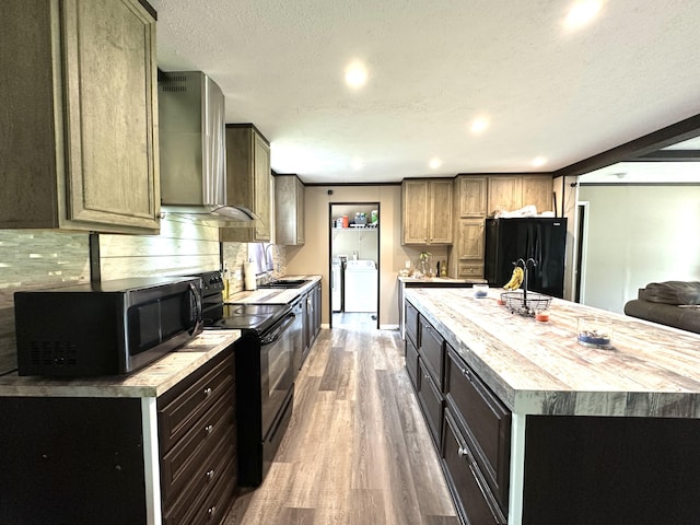 1126 College Hill Rd, Waco, KY 40385 - kitchen with black appliances, wall chimney exhaust hood, washer / dryer, wood finished floors, and light countertops