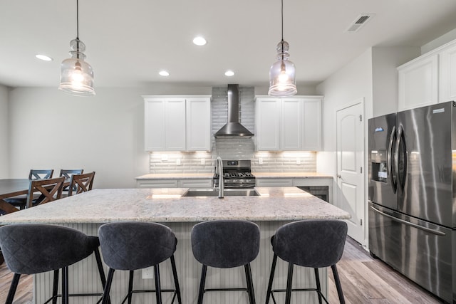 216 Blackthorn Dr, Nicholasville, KY 40356 - kitchen with stainless steel appliances, wall chimney exhaust hood, decorative backsplash, a center island with sink, and light wood-type flooring