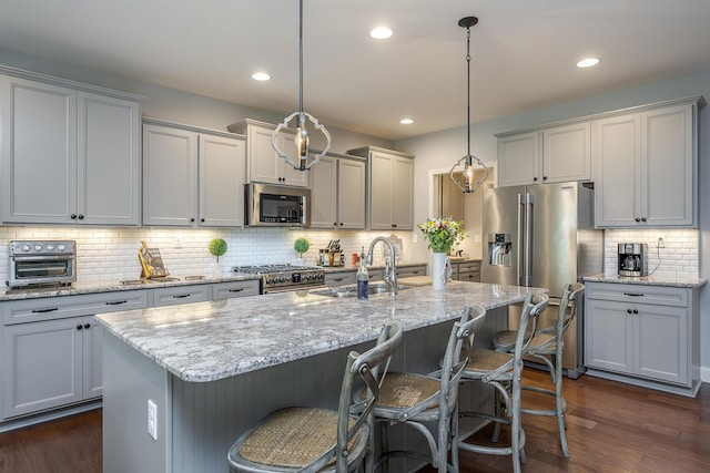 320 Manitoba Ln, Lexington, KY 40515 - kitchen featuring appliances with stainless steel finishes, a sink, decorative backsplash, dark wood finished floors, and a kitchen breakfast bar