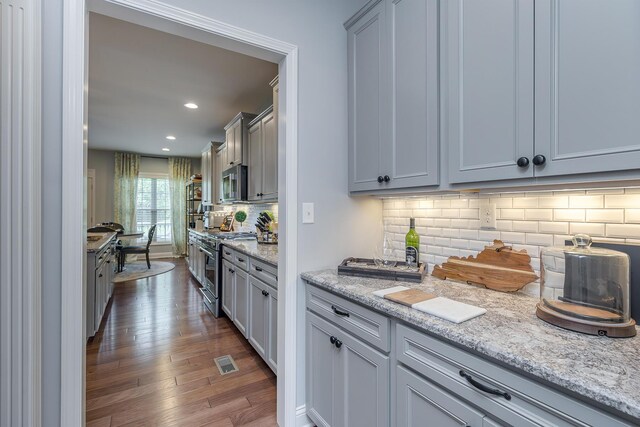 320 Manitoba Ln, Lexington, KY 40515 - kitchen featuring appliances with stainless steel finishes, dark wood-type flooring, tasteful backsplash, light stone countertops, and recessed lighting