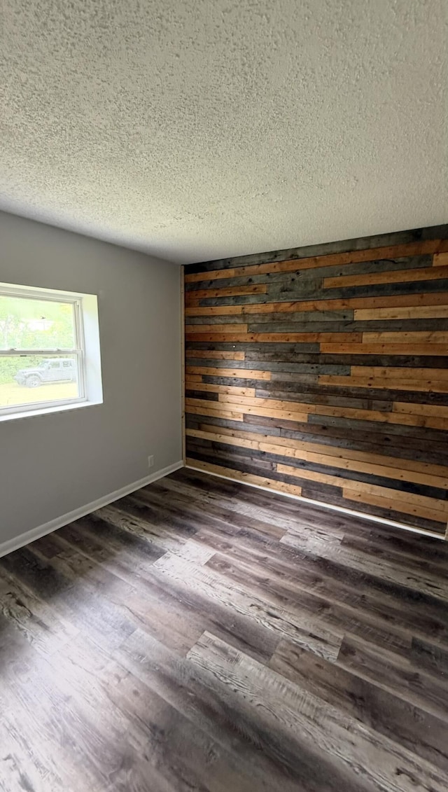 606 Prospect St, Berea, KY 40403 - unfurnished room with a textured ceiling, dark wood finished floors, baseboards, and wooden walls